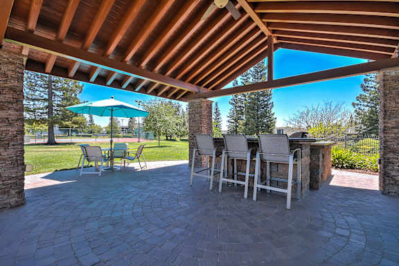A patio with a table and chairs under a wooden roof at Rosemeade Apartments, Roseville, 95661