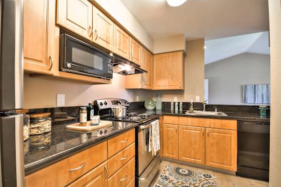 A kitchen with wooden cabinets and black countertops at Rosemeade Apartments, Roseville, 95661