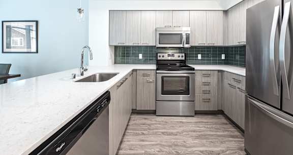 A modern kitchen with a stainless steel refrigerator, oven, and sink.