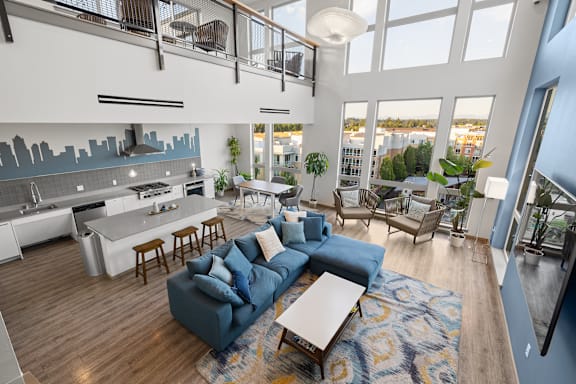 A modern living room with a blue couch and a kitchen area with a city skyline backsplash.