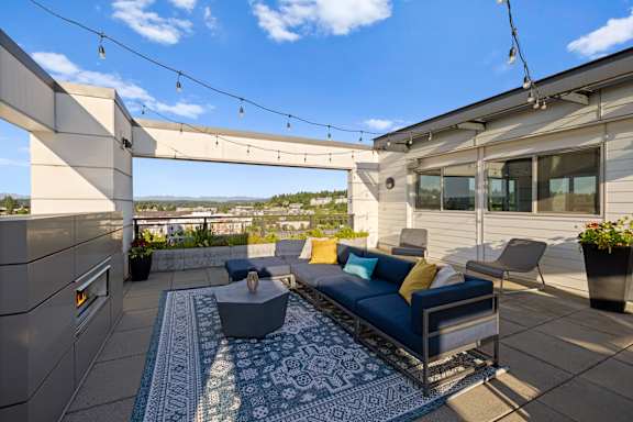 A modern outdoor patio with a blue couch and a coffee table.
