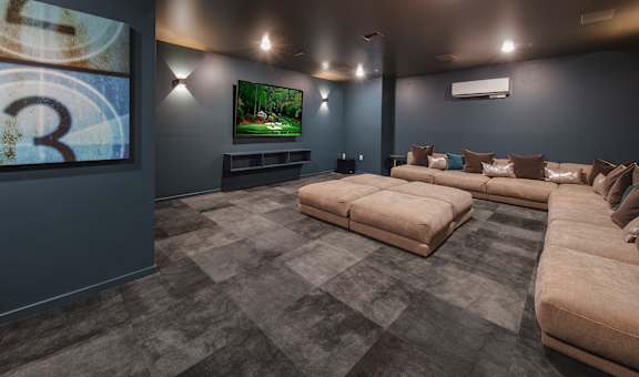 A modern theater screening room with a large television and comfortable seating.