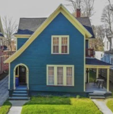A blue house with a yellow roof and a porch.