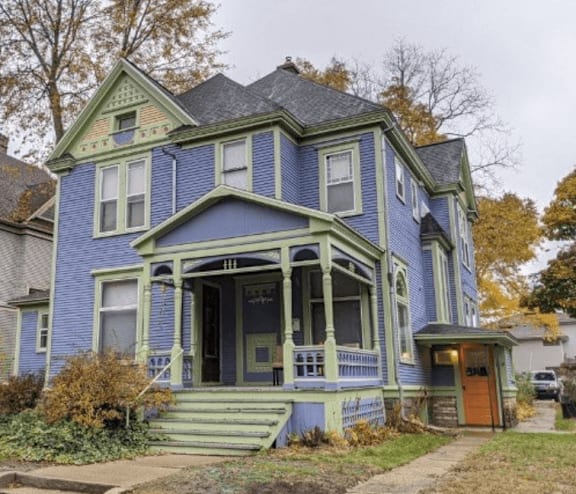 A blue house with a green trim and a brown door.