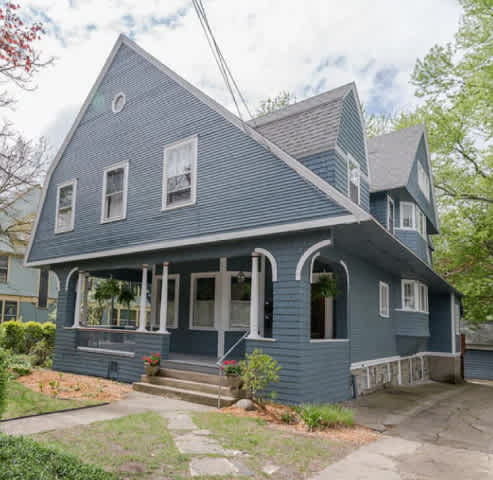 A blue house with a porch and a front yard.