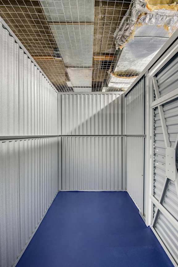 A blue mat is on the floor of a room with a metal wall.