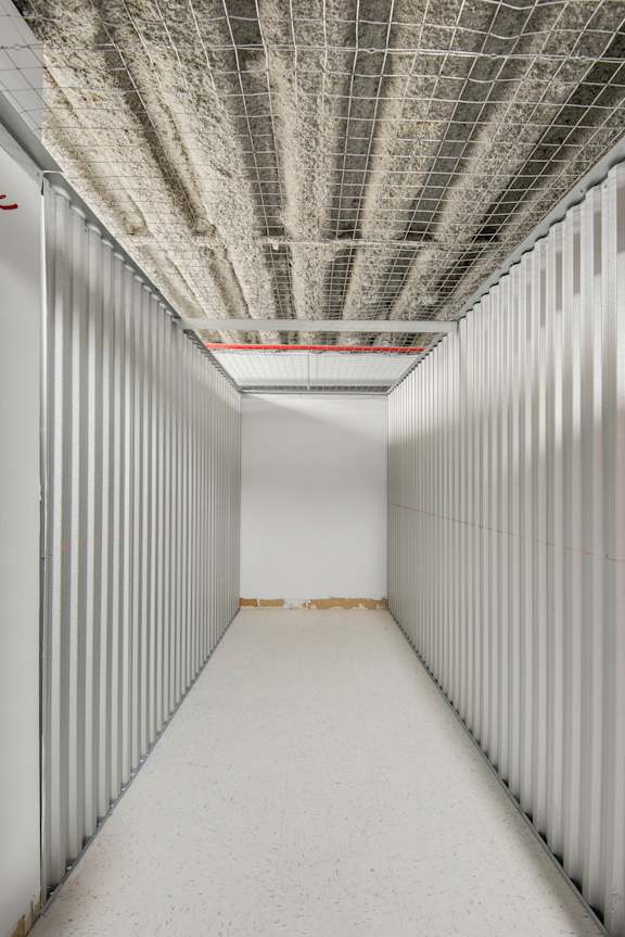 A long, narrow room with a white ceiling and walls, and a metal grid on the ceiling.