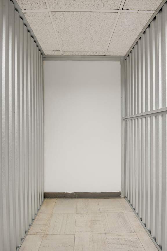 A long, narrow hallway with white walls and a tiled floor.