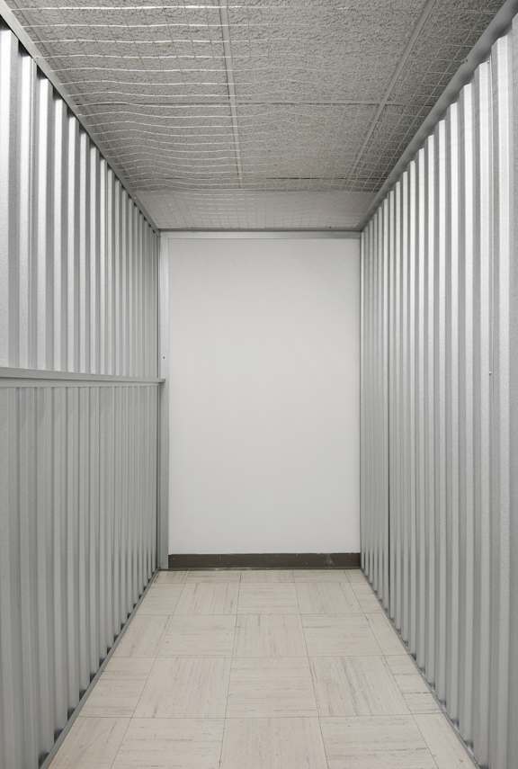 A long hallway with white walls and grey floor tiles.