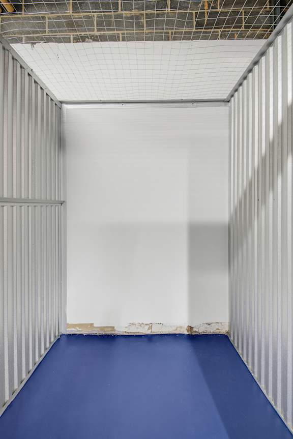 A long, narrow room with a blue floor and white walls.