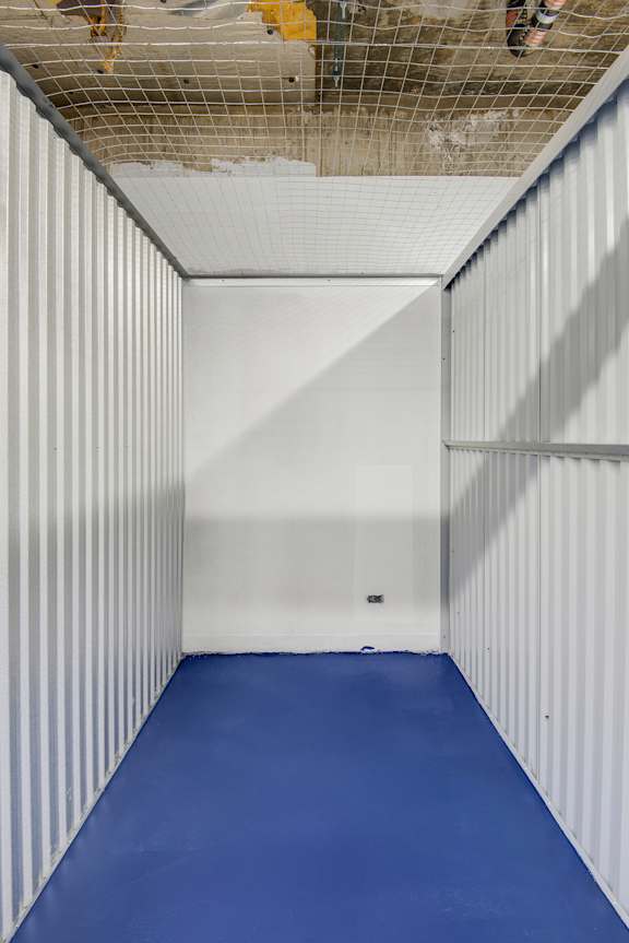A long, narrow room with a blue floor and white walls.