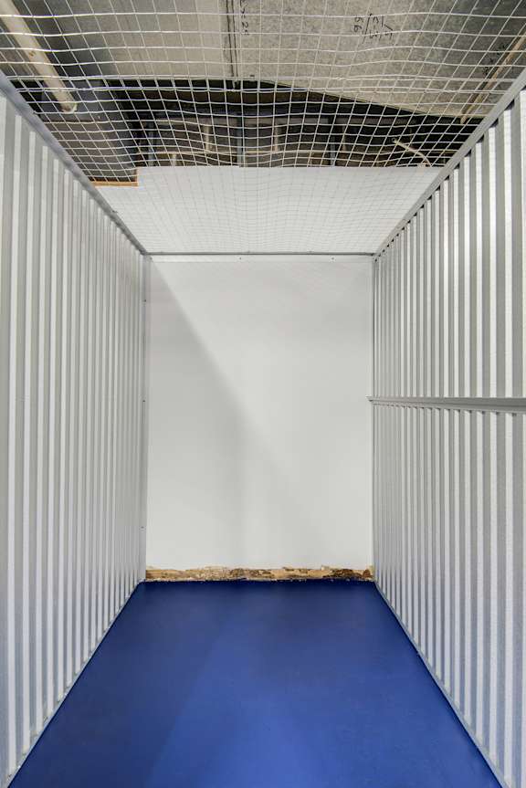A long, narrow room with a blue floor and white walls.