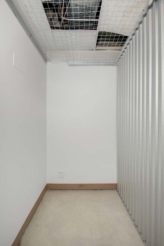 A room with a white wall and a brown baseboard.
