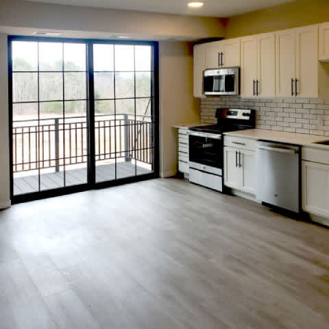 A kitchen with white appliances and a balcony with glass doors.