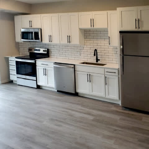 A kitchen with white cabinets and a black fridge.