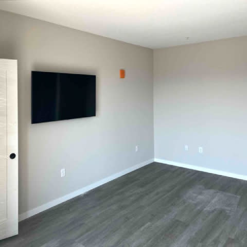 A room with a flat screen TV mounted on the wall and a wooden floor.