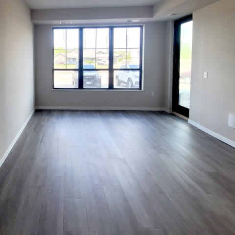 A room with a large window and grey flooring.