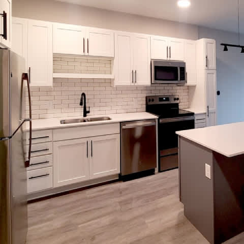 A kitchen with white cabinets and a black stove top oven.