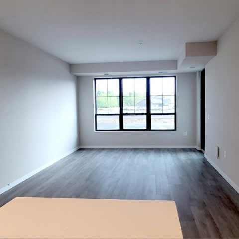 A room with a large window and a table in the foreground.