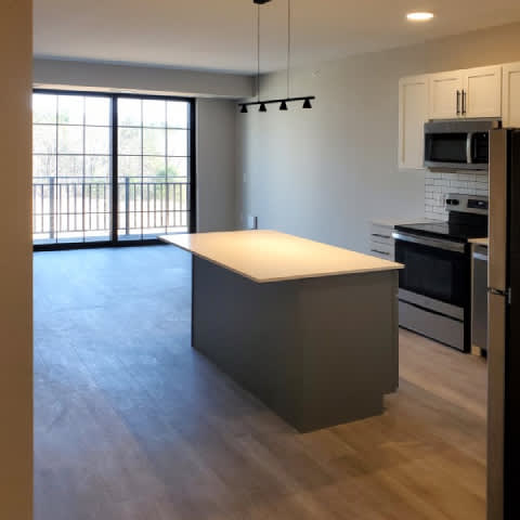 A kitchen with a white counter top and wooden floors.