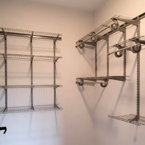A wall-mounted metal shelving unit with wheels on the bottom.