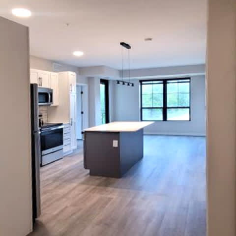 A kitchen with a refrigerator, microwave, oven and a counter top.