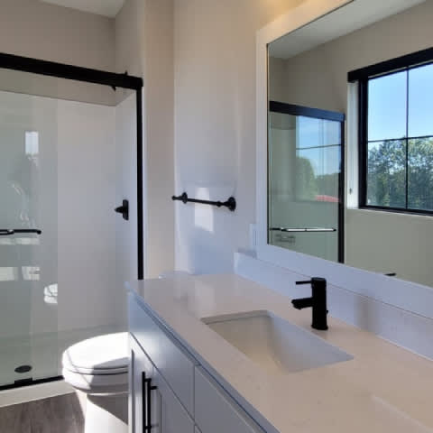 A modern bathroom with a toilet, sink, and mirror.