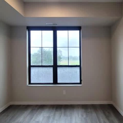 A room with a large window and a view of trees outside.