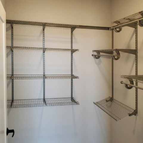 A metal shelving unit with four shelves is mounted on a white wall.