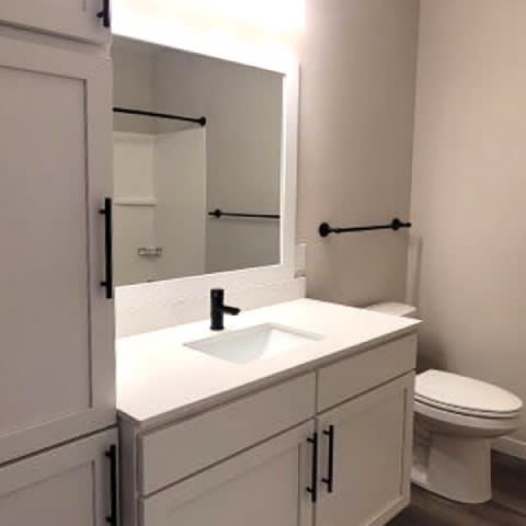 A white bathroom with a toilet, sink, and mirror.