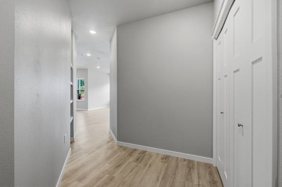 A long hallway with white walls and wood flooring.
