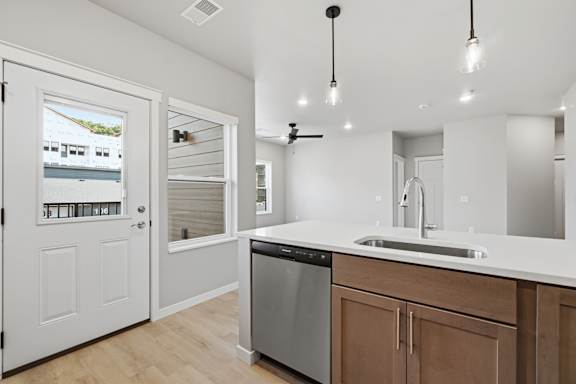 A modern kitchen with wooden cabinets and a stainless steel dishwasher.