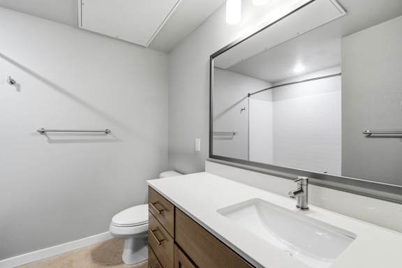 A bathroom with a white sink, toilet, and mirror.