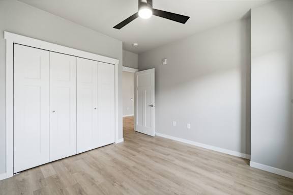 A room with a ceiling fan and a white door.