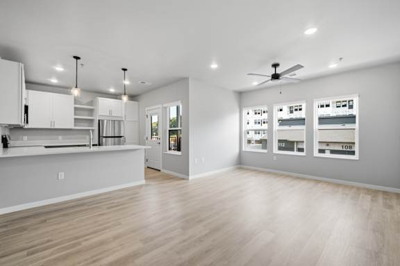 A spacious kitchen with a bar area and a ceiling fan.