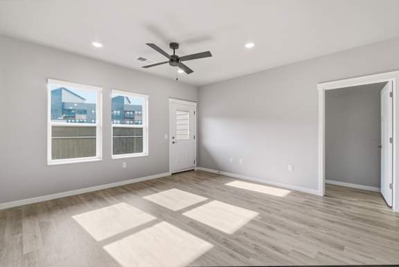 A room with a ceiling fan and a large window.