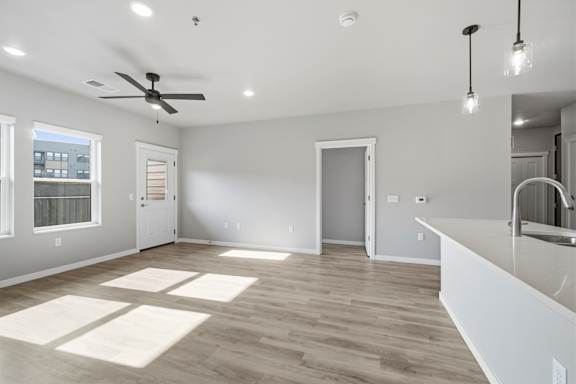 A spacious room with a ceiling fan and lighting fixtures.