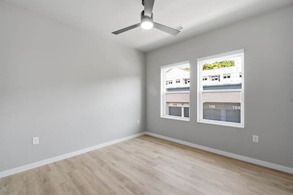 A room with a ceiling fan and two windows.