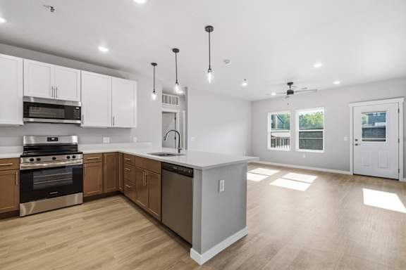 A modern kitchen with wooden floors and stainless steel appliances.