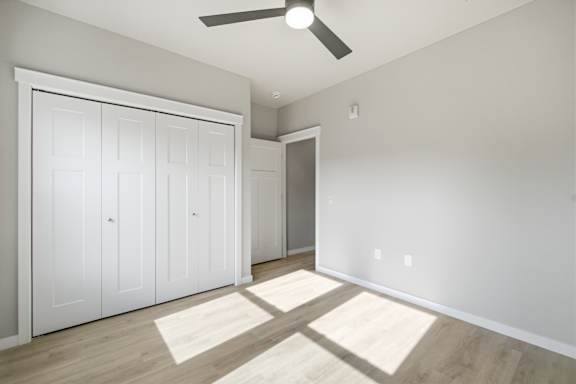 A room with a ceiling fan and two white doors.