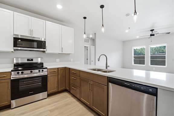 A modern kitchen with a stainless steel dishwasher and wooden cabinets.