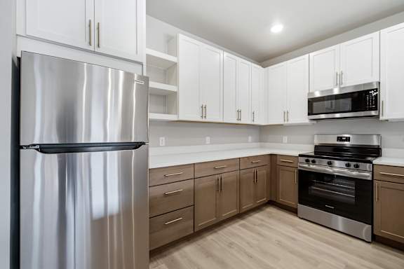 A modern kitchen with a stainless steel refrigerator and wooden floors.