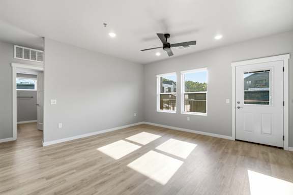 A room with a ceiling fan and a window with a view of a building.