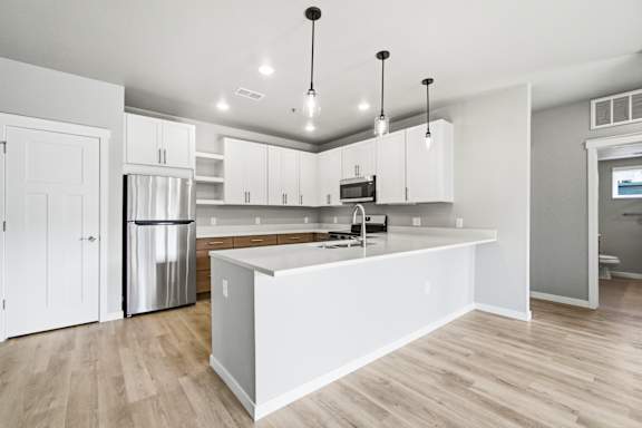 A kitchen with white cabinets and a wooden floor.