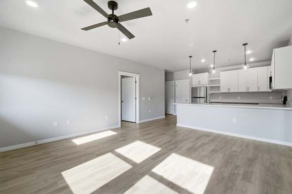A spacious room with a ceiling fan and wooden flooring.