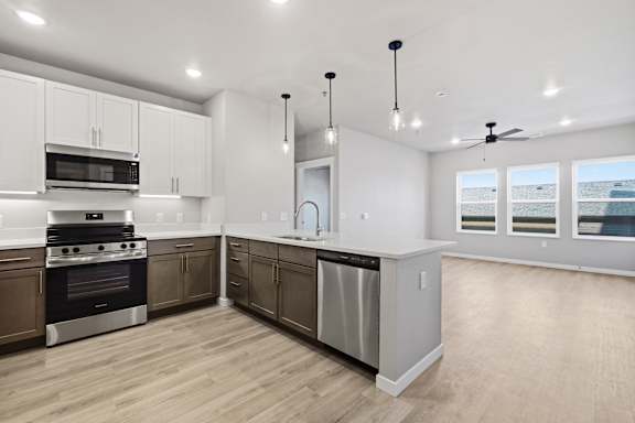 A modern kitchen with wooden floors and stainless steel appliances.