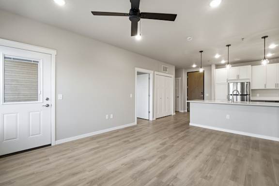 A room with a ceiling fan and wooden flooring.