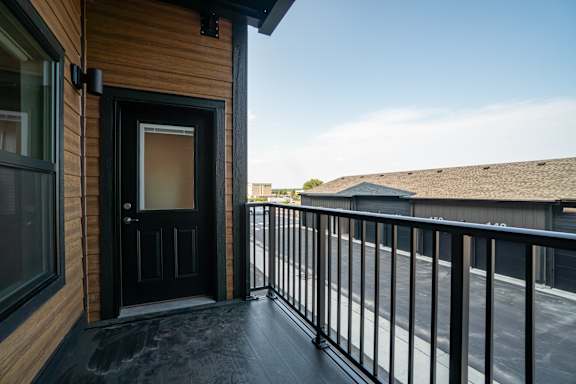 A balcony with a black railing and a black door.