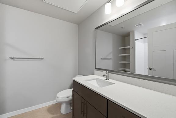 A bathroom with a toilet, sink, and mirror.