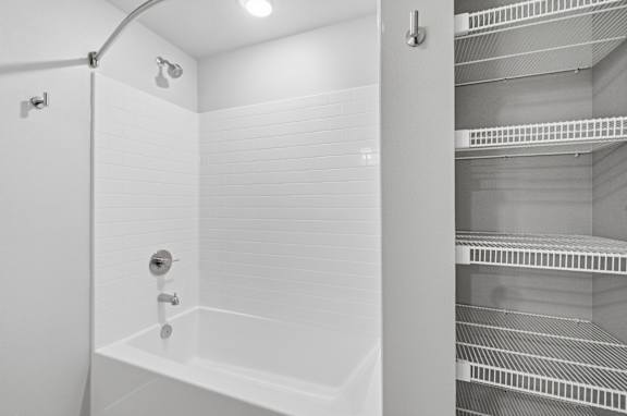 A white bathroom with a shower and a refrigerator.